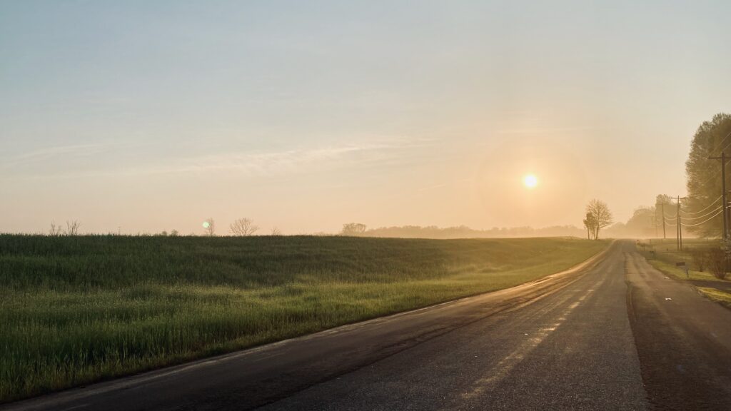 Suburban road with a sunrise and fog.